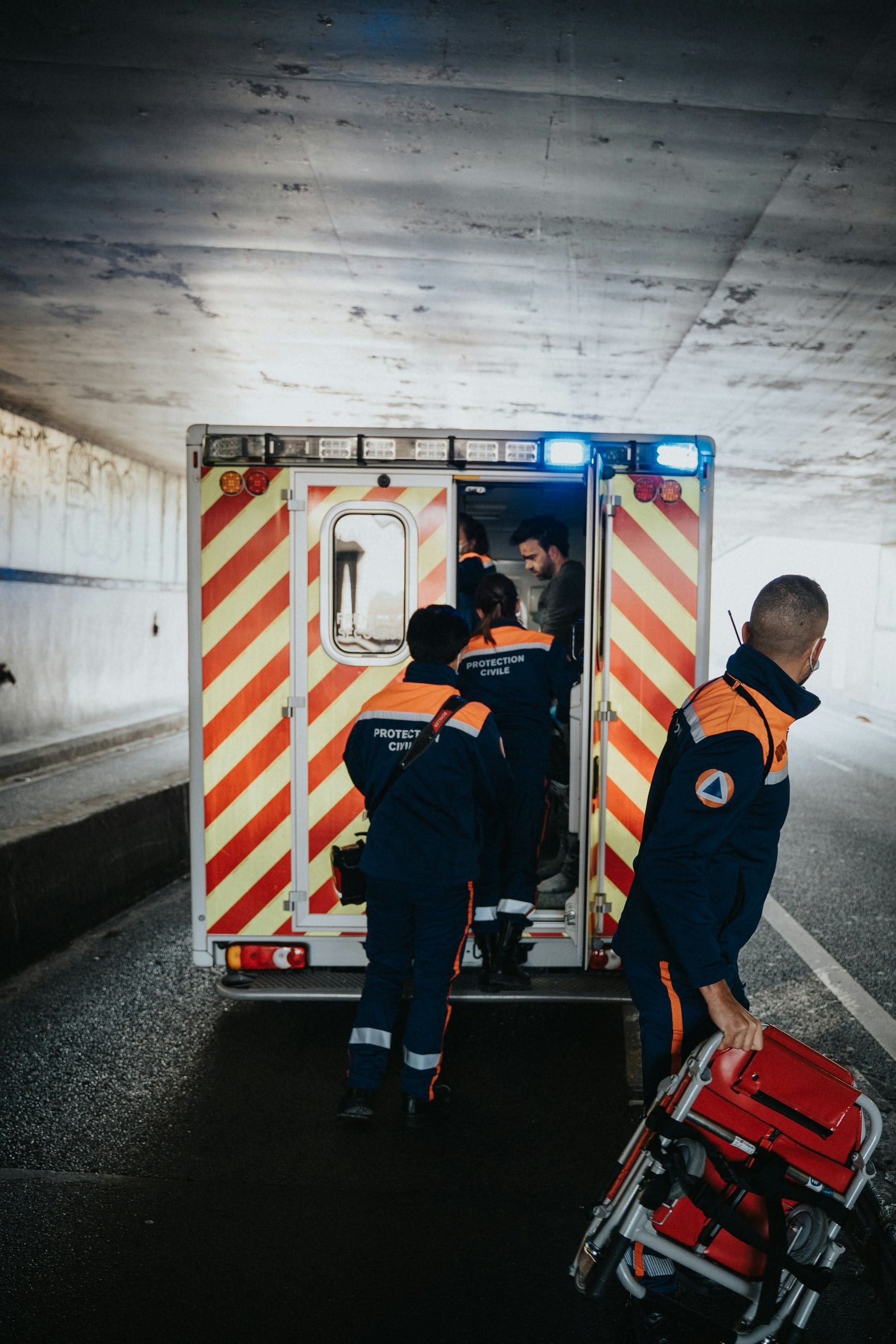 An emergency response crew loading equipment into the back of an ambulance in a road tunnel.